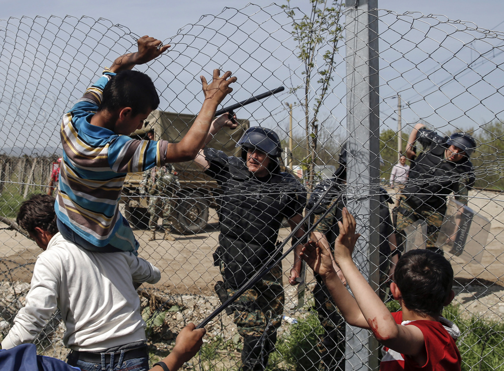 A Macedonian policeman uses his baton to prevent migrants and refugees to open the border fence at a makeshift camp at the Greek-Macedonian border near the village of Idomeni, Greece, April 7, 2016. REUTERS/Marko Djurica      TPX IMAGES OF THE DAY      - RTSE10V